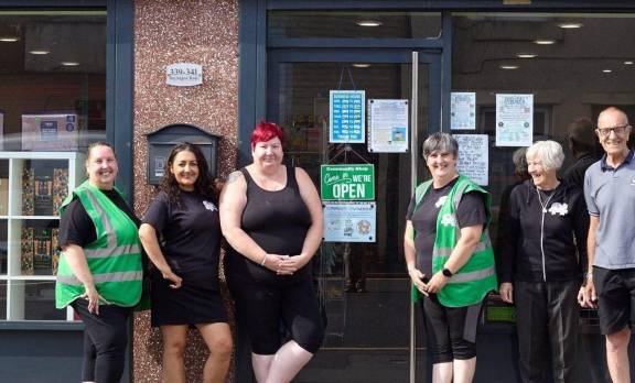 Six members of the team standing in front of The Big Local Community Shop storefront, underneath the large storefront sign.