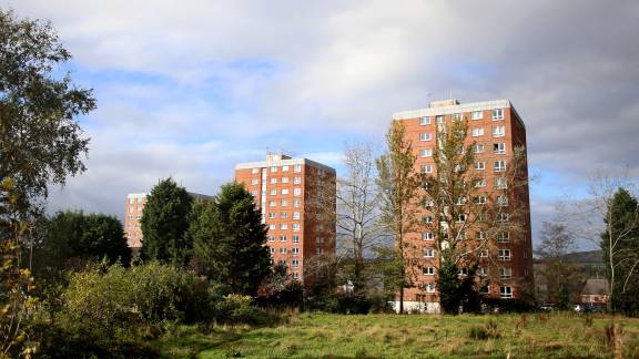 Green space with three brick blocks of flats in the background.