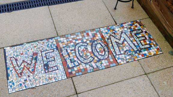A colourful mosaic on a tile floor reads 'Welcome'.