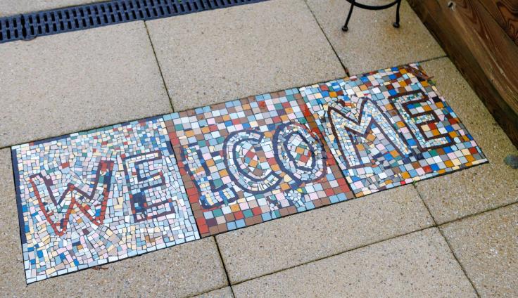 A colourful mosaic on a tile floor reads 'Welcome'.