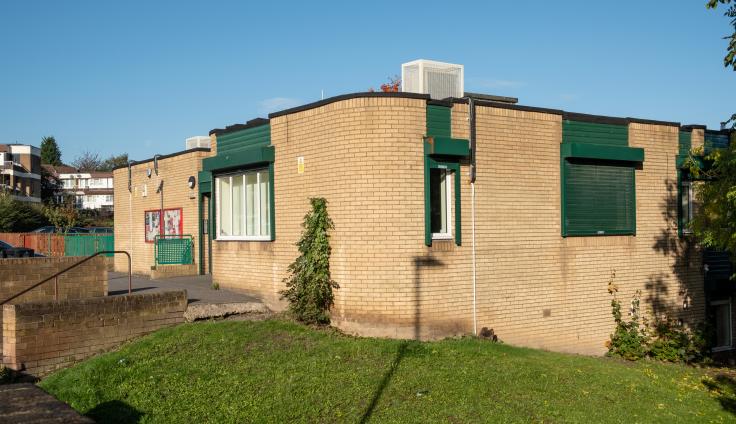 The community centre, a brick building with grass and trees in front.
