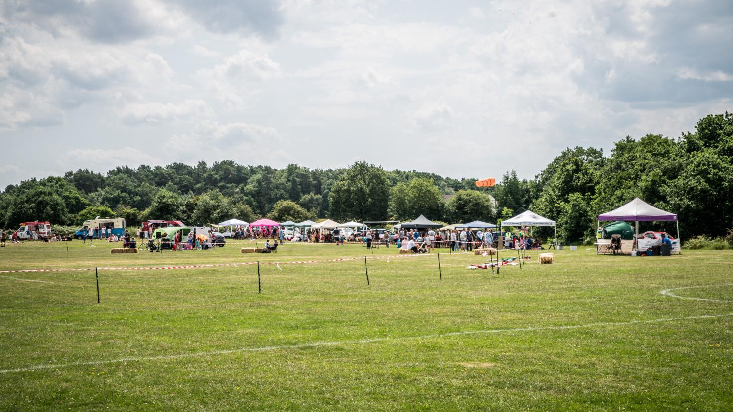 A festival in a large field, with stalls and pergolas.