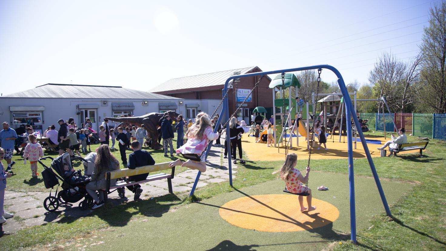 A busy play park showing families and children on swings.