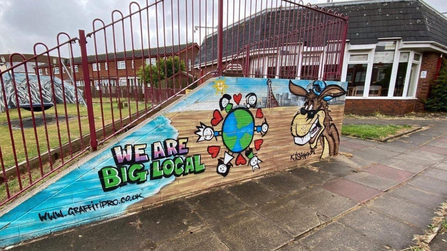 A colourful spray art mural on the side of a concrete slope, which reads 'We are Big Local'.