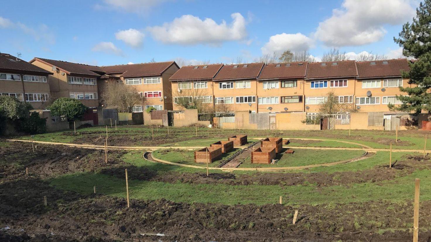 A green space in the middle of a housing area which has been marked out with newly dug borders.