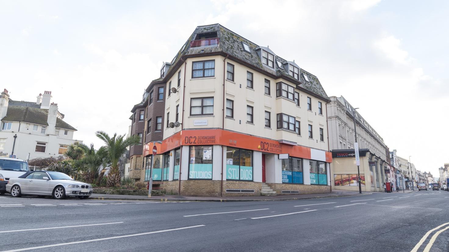 A four-storey cream building with the words "DC2 Devonshire Collective" on a red sign.