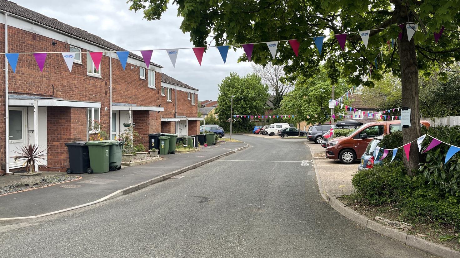 Two-storey residential buildings with a road and coloured bunting