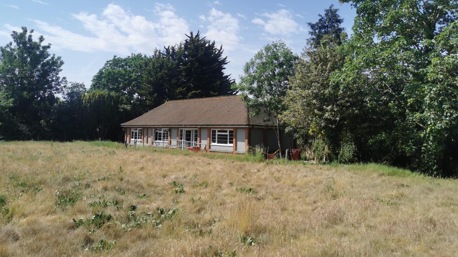 A single-storey red brick building surrounded by green space.