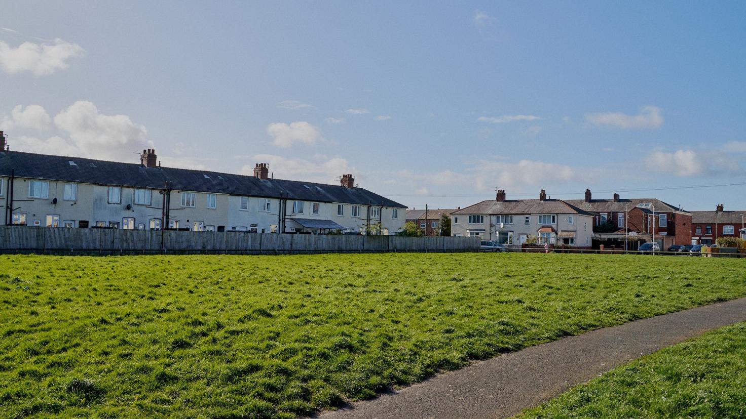 A large grassy recreation area in front of houses.