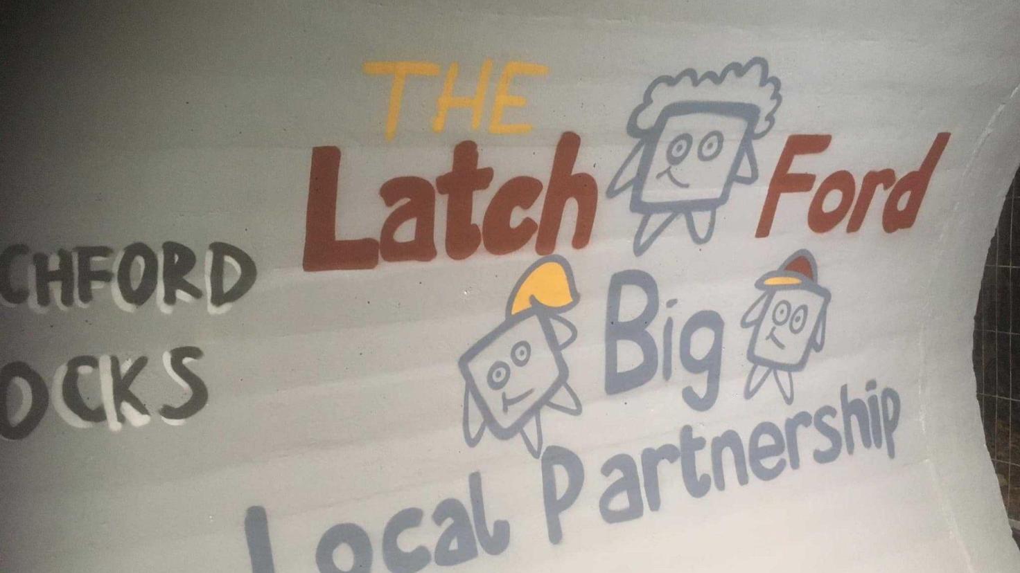 A mural in an underground pedestrian walkway that says 'The Latch Ford Big Local Partnership'.