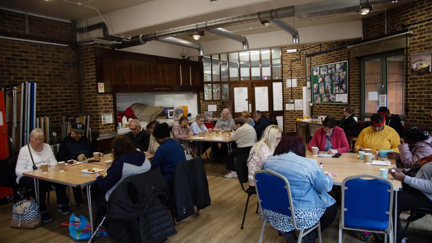 A group of people sitting down in a room at tables.