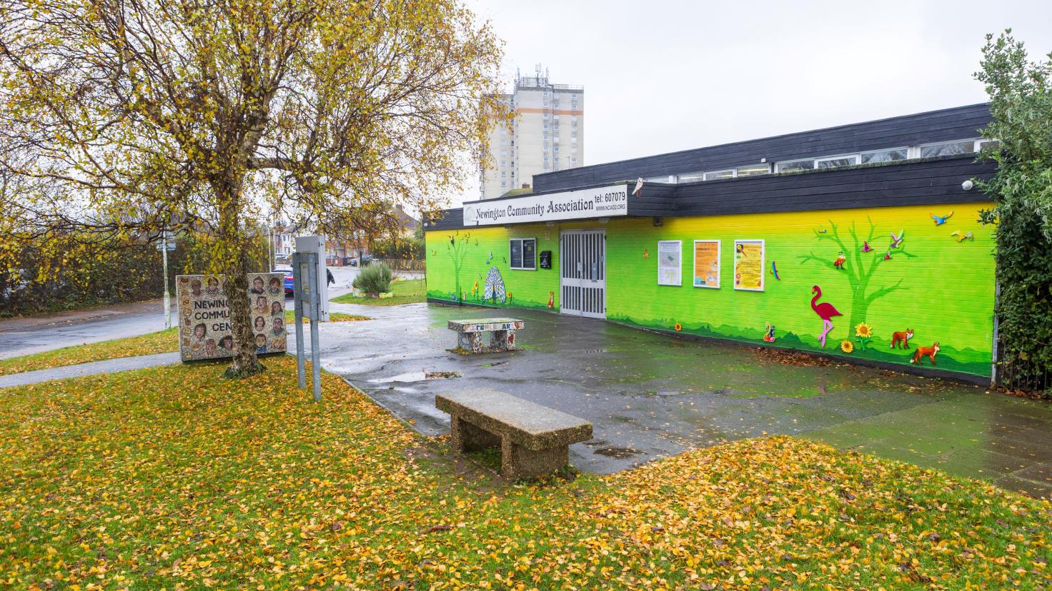 A single-storey building with a colourful mural of a nature scene painted on the side.