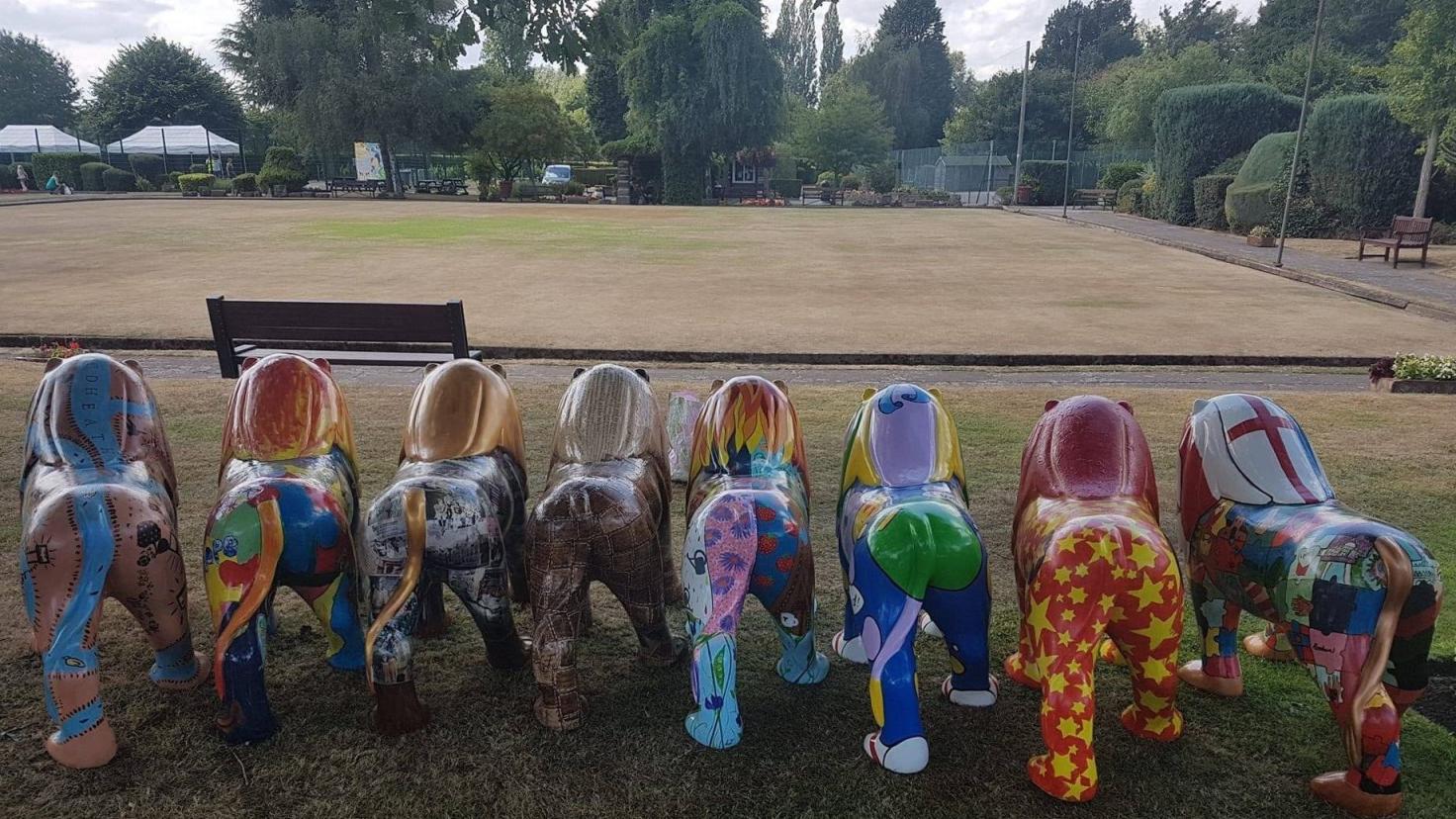 Eight uniquely painted lion sculptures with a bowls green in the background.