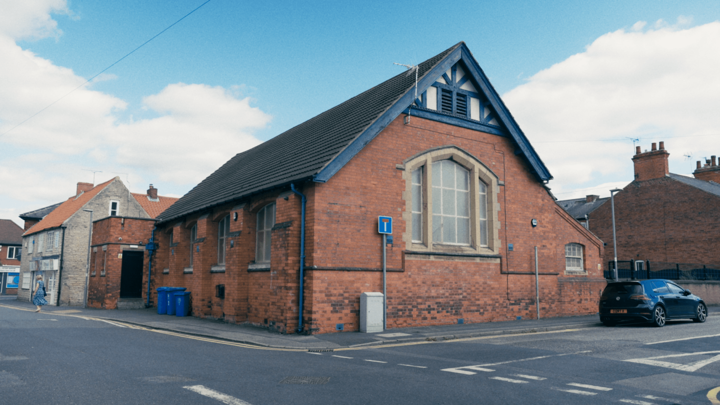 A red-brick church hall style building on a road junction.