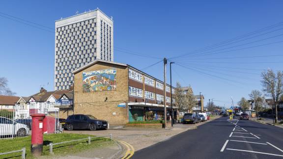 A streetscape with a tower block in the background and a row of 1960s terraced houses in the foreground.