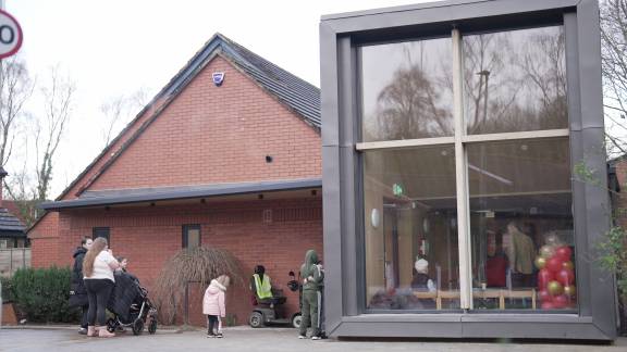 A modern red-brick building with a glass rectangular extension with large windows.