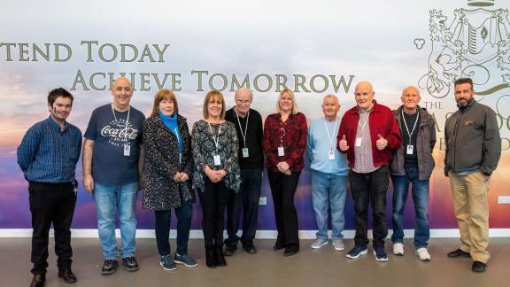 Ten people standing in a semi-circle and smiling.