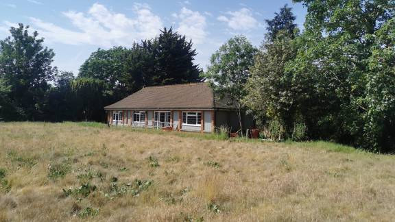 A single-storey red brick building surrounded by green space.