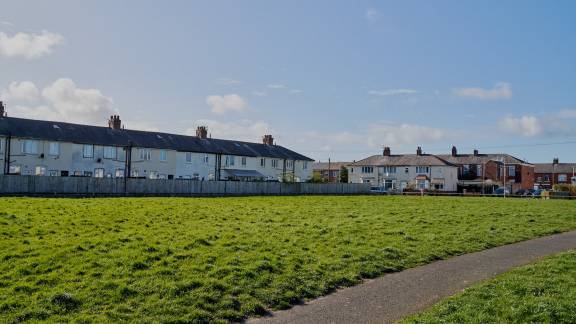 A large grassy recreation area in front of houses.