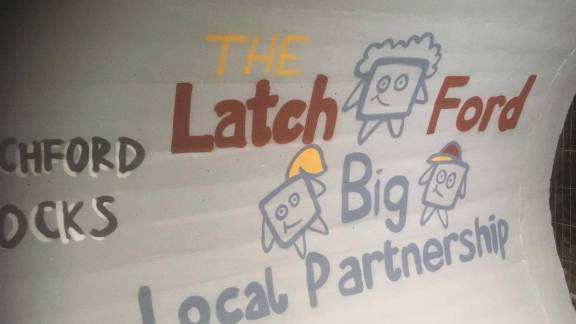 A mural in an underground pedestrian walkway that says 'The Latch Ford Big Local Partnership'.