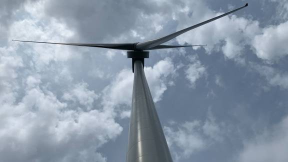 Looking up at a wind turbine with the main tower and 3 blades above.