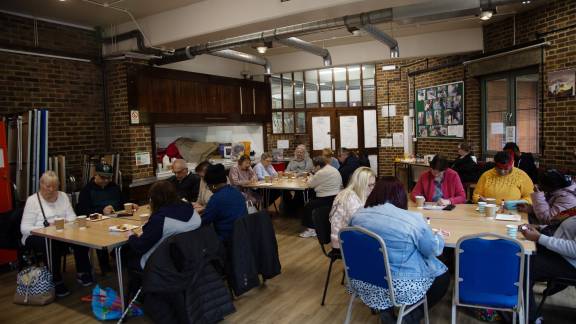 A group of people sitting down in a room at tables.