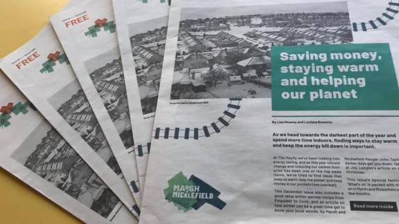 Five copies of a newspaper are laid out in a fan pattern on a yellow table. The top left-hand corner says "FREE" in. red letters. The top copy in a green box shows a front page with the headline "Saving money, staying warm and helping the planet". A black and white photo of houses is behind it. The Marsh & Micklefield logo is in the bottom left of the page.