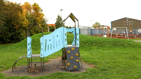 Playground equipment including a slide in a green area.