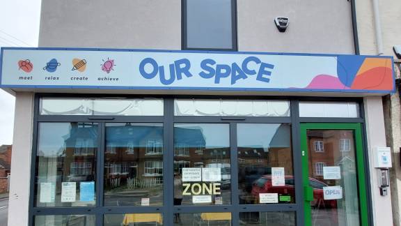 A modern shop front below a colourful sign reading 'Our Space.'