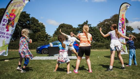 Children exercising in a group on a sunny playing field.