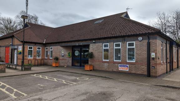 One-storey brick building with a brown tiled roof and a sign reading 'Tang Hall Big Local'