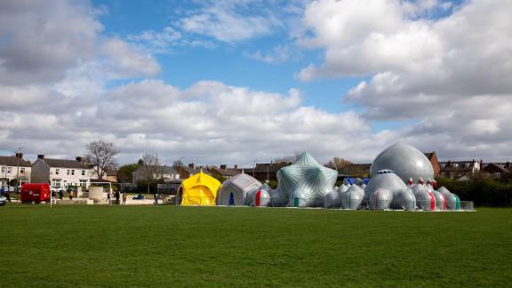 Large green space with grey inflatable sculpture in the background