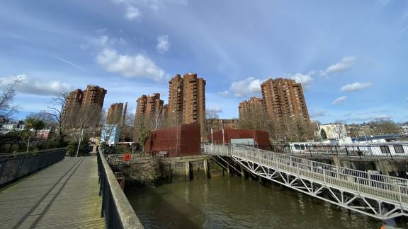 A view of red-brick towers in the distance, over a body of water with bridges.