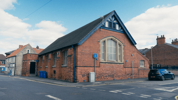 A red-brick church hall style building on a road junction.