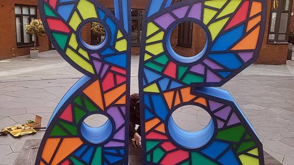 A large bright sculpture of a butterfly, painted with a colourful stained-glass effect.