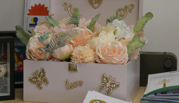 A pink jewelry-type box with decoupage on the outside and peach paper roses displayed inside.