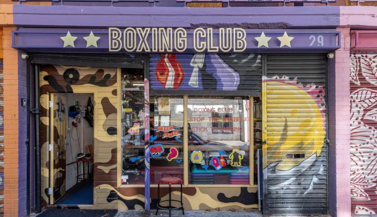 A shop-front painted in pinks and purples with a sign reading 'Boxing Club' above the doorway.
