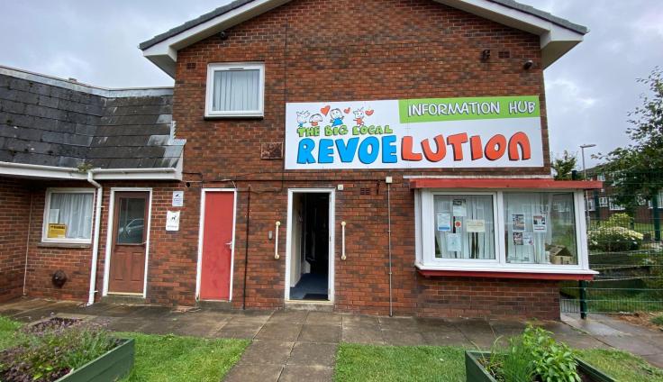 A two-storey red brick building with a colourful Revoelution banner above the door.