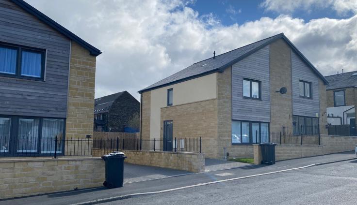 A two-storey gable-ended house with wooden cladding and dark-framed windows.