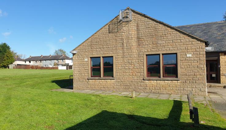 A single-storey brick building on a sunny, grassy plot.
