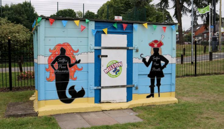 A colourful wooden shack, painted with silhouettes of a mermaid and a pirate.