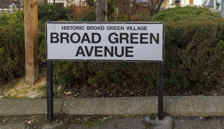 A street sign reading "Historic Broad Green Village: Broad Green Avenue."