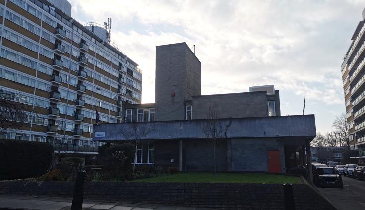 A multi-story housing estate building adjacent to a road.