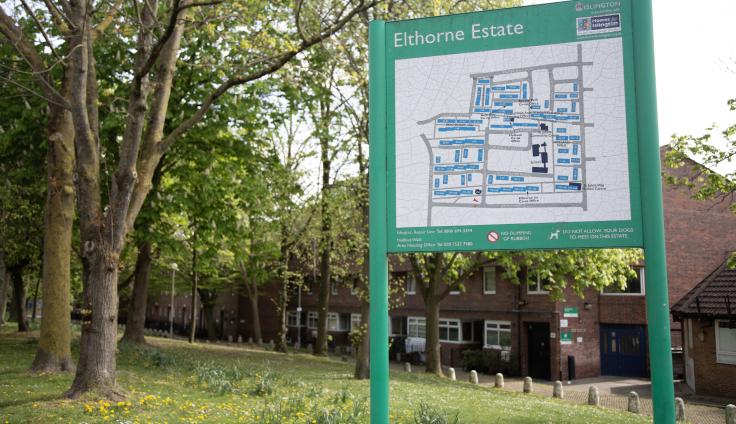 A green sign next to trees and houses that shows a map of the Elthorne Estate.