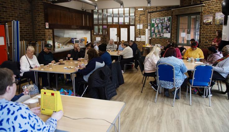 People sitting around tables, looking down at bingo cards.