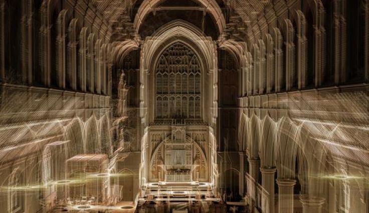 Gold lights are projected around the nave of a church to create new shapes on existing architecture.