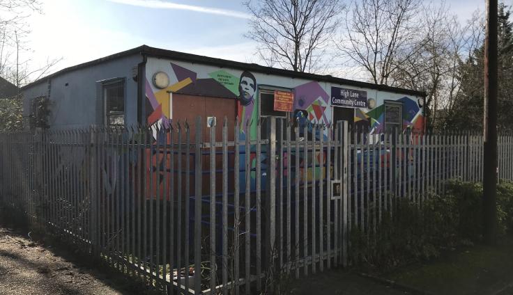 A colourful single-storey building behind metal railings.
