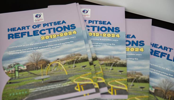 A handful of Heart of Pitsea Reflections magazines fanned out on a table.