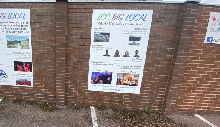 Two posters on a brick wall displaying the contributions that LCC Big Local made