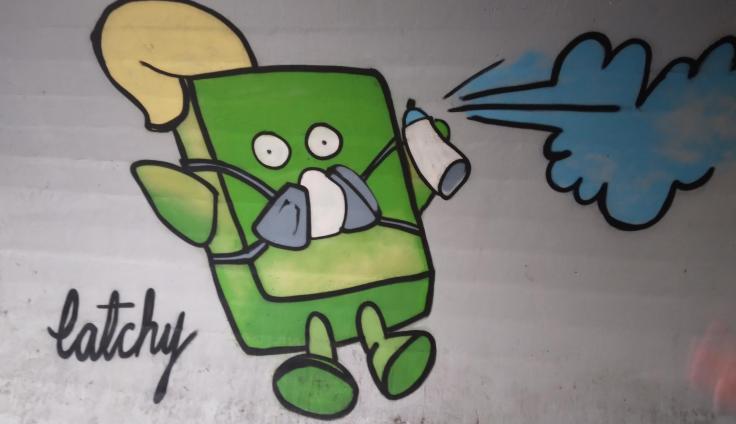 A mural showing a cuboid-shaped green cartoon character jumping into the air with an aerosol can.
